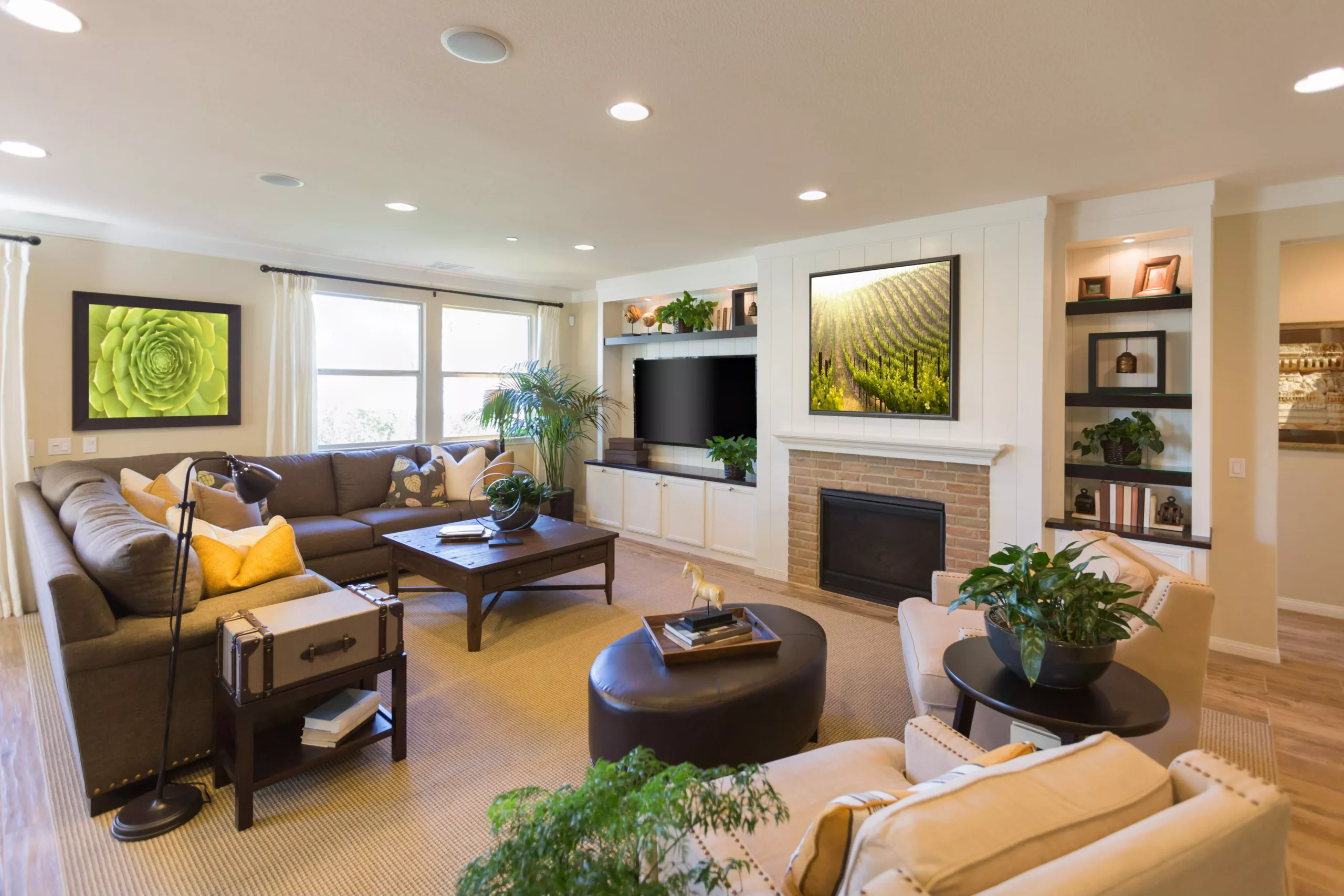 Bright, modern living room with brown sectional, yellow pillows, dark wood furniture, fireplace, TV, and potted plants.